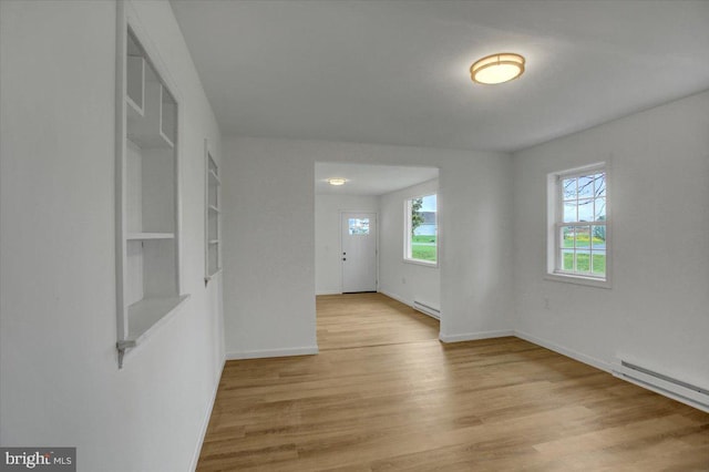unfurnished room with light wood finished floors, baseboard heating, a baseboard heating unit, and baseboards