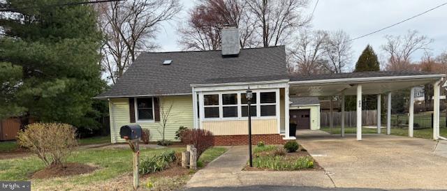 bungalow-style home featuring concrete driveway, fence, a chimney, and a carport