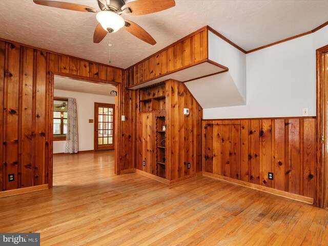 bonus room featuring a ceiling fan, wood walls, and wood finished floors