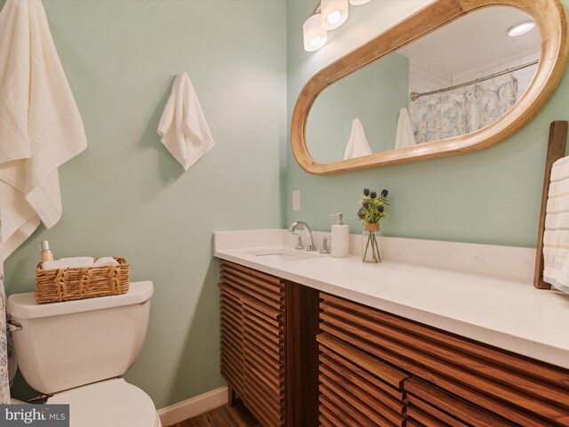 bathroom with vanity, baseboards, wood finished floors, and toilet
