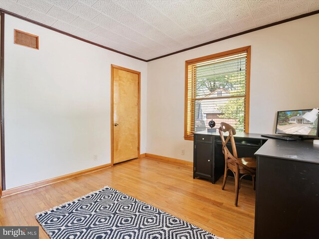 office with baseboards, ornamental molding, light wood-type flooring, and visible vents