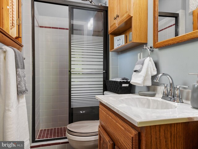 full bathroom featuring vanity, a shower stall, and toilet