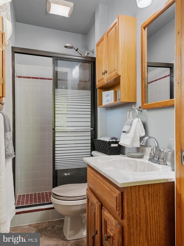 full bath featuring vanity, tile patterned flooring, a stall shower, and toilet