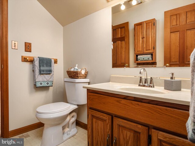 bathroom featuring vanity, toilet, tile patterned floors, baseboards, and vaulted ceiling