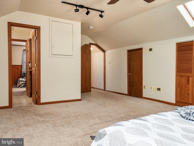 bedroom with track lighting, baseboards, vaulted ceiling with skylight, and light colored carpet
