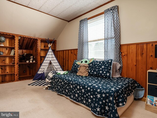 bedroom featuring wooden walls, wainscoting, carpet, vaulted ceiling, and ornamental molding