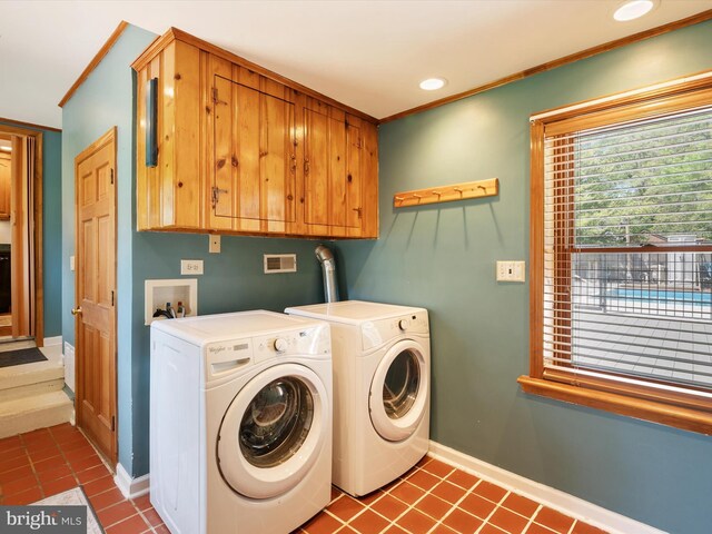 clothes washing area featuring dark tile patterned floors, crown molding, cabinet space, baseboards, and washer and clothes dryer