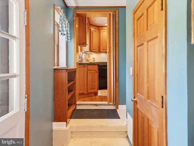 hall with baseboards, a sink, and wood finished floors