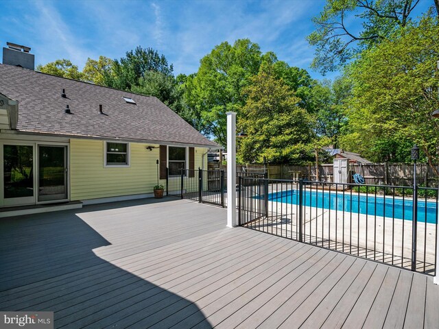 wooden deck featuring a fenced backyard, a fenced in pool, an outdoor structure, and a storage shed