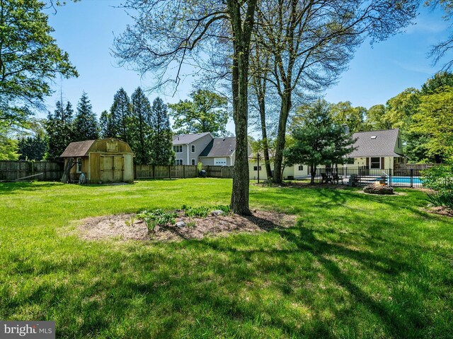 view of yard with a fenced backyard, a fenced in pool, an outbuilding, and a shed