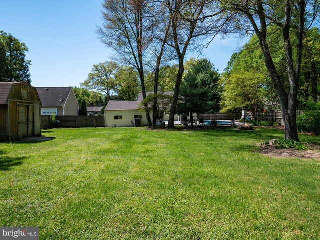 view of yard featuring a storage shed, an outdoor structure, and a fenced backyard