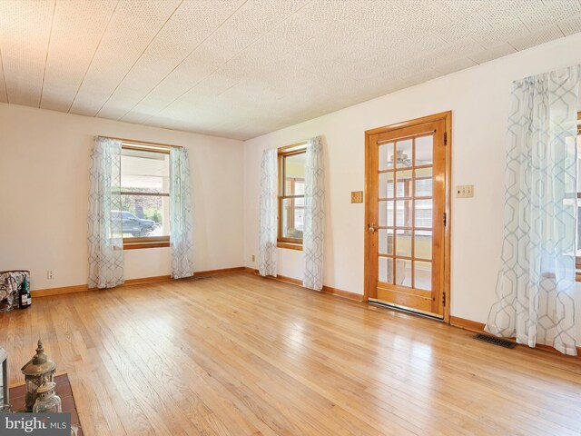unfurnished room featuring visible vents, baseboards, and hardwood / wood-style floors