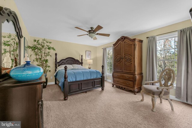 bedroom featuring light colored carpet, ceiling fan, baseboards, and multiple windows