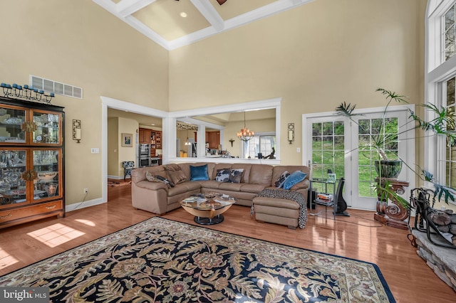 living room with beamed ceiling, wood finished floors, visible vents, and a high ceiling