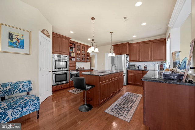 kitchen featuring a sink, visible vents, wood finished floors, a kitchen island, and appliances with stainless steel finishes