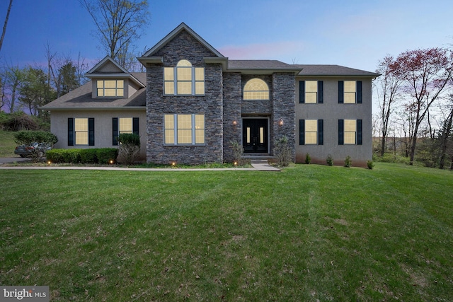 traditional-style house with stone siding, a front yard, and stucco siding