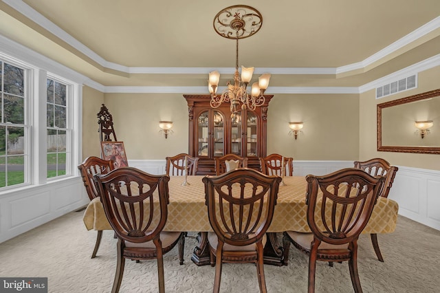 dining room with a chandelier, a raised ceiling, visible vents, and a decorative wall