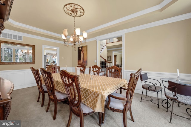 dining room featuring a tray ceiling, visible vents, light carpet, ornamental molding, and a notable chandelier