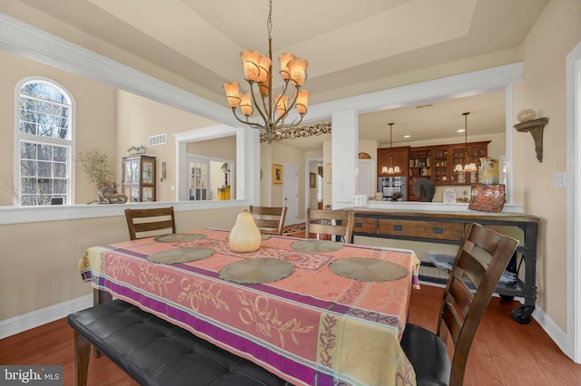 dining room with baseboards, wood finished floors, visible vents, and an inviting chandelier