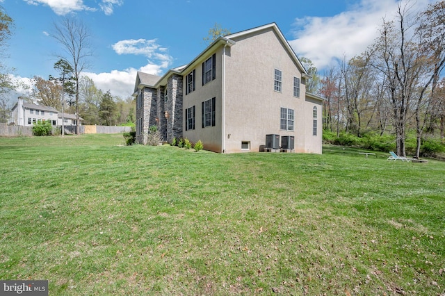 view of side of home featuring a lawn, stucco siding, and fence