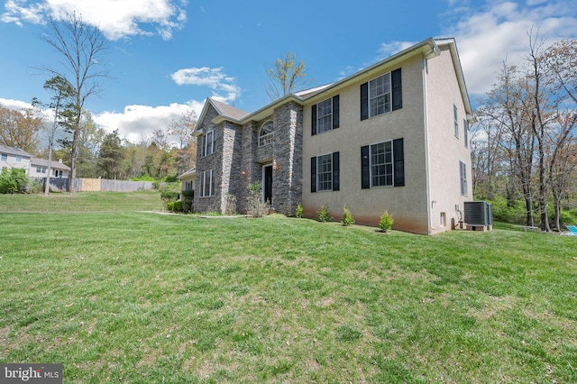 colonial inspired home with stucco siding, a front lawn, fence, and cooling unit