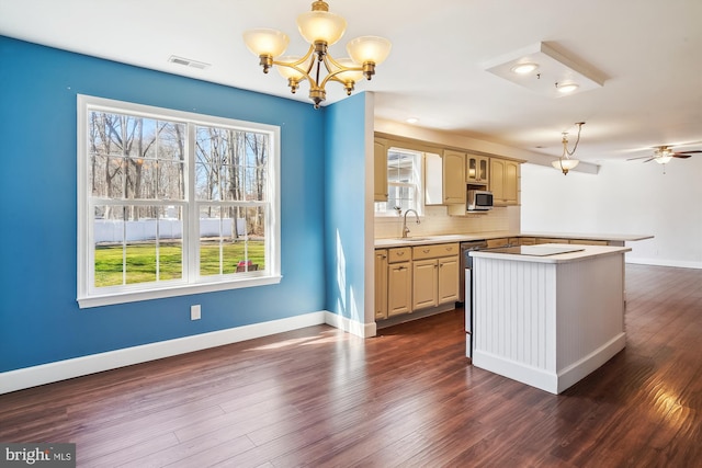 kitchen with light countertops, visible vents, a sink, dark wood-type flooring, and decorative backsplash