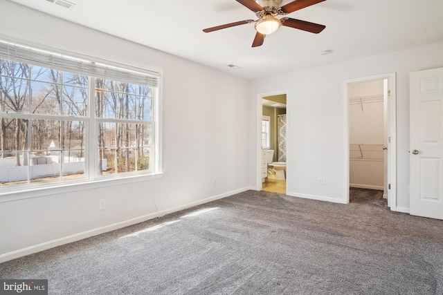 unfurnished bedroom featuring carpet flooring, baseboards, a spacious closet, a closet, and ensuite bath