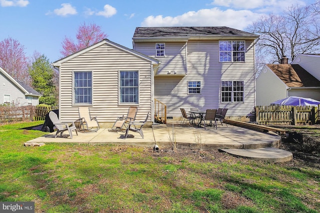 rear view of property featuring fence, a yard, and a patio