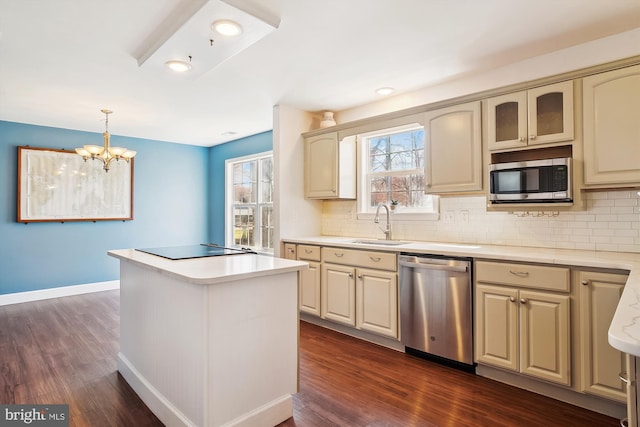 kitchen with stainless steel appliances, a sink, dark wood finished floors, an inviting chandelier, and light countertops