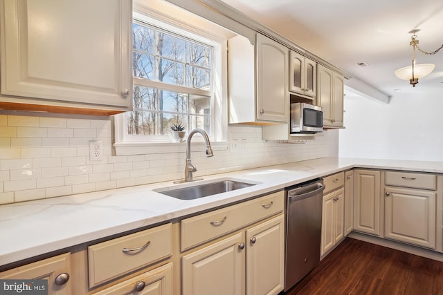 kitchen featuring stainless steel appliances, a sink, dark wood-style flooring, backsplash, and light stone counters