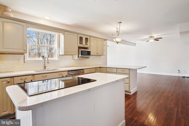kitchen with a peninsula, a sink, tasteful backsplash, dark wood-type flooring, and appliances with stainless steel finishes