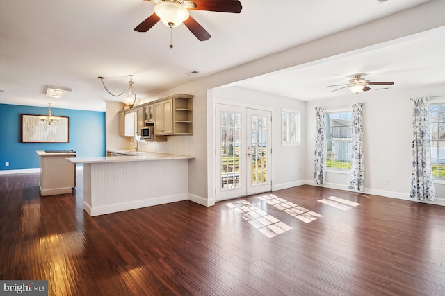 unfurnished living room with dark wood finished floors, a sink, and ceiling fan with notable chandelier
