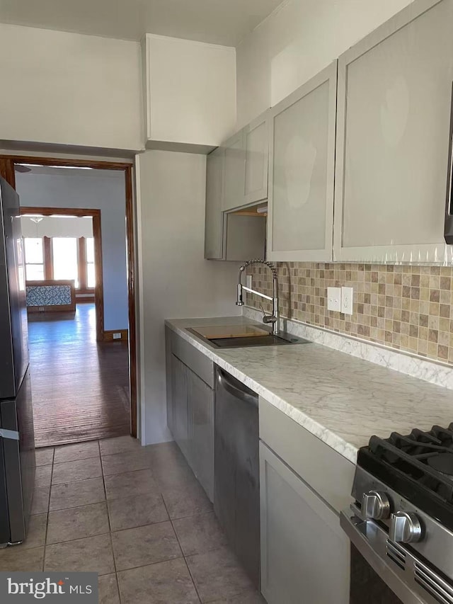 kitchen featuring gray cabinets, a sink, decorative backsplash, appliances with stainless steel finishes, and tile patterned floors