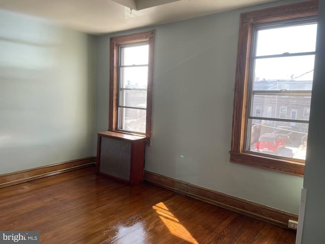 spare room with radiator, baseboards, and wood finished floors
