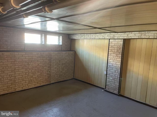 below grade area featuring tile patterned floors and brick wall
