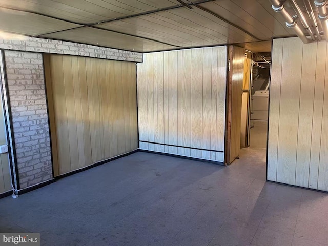 empty room featuring washer / dryer, wooden walls, and wood ceiling