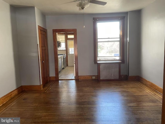 unfurnished room featuring radiator, light wood-style floors, plenty of natural light, and ceiling fan
