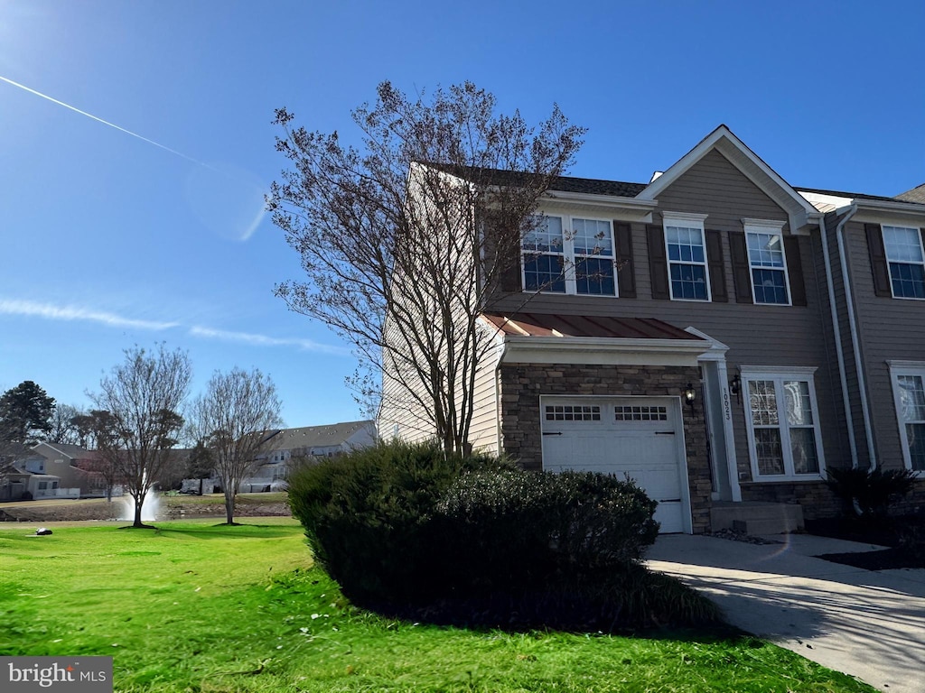 view of front of home with a front yard, stone siding, and a garage