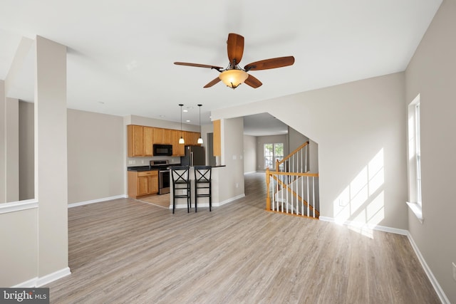 10023 Iron Pointe Drive Ext Unit 201B2, Millsboro, DE 19966 - unfurnished living room with light wood-style flooring, baseboards, ceiling fan, and stairway