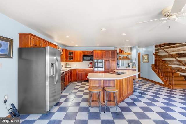 1460 Pitcock Ln, Winchester, VA 22602 - kitchen with a breakfast bar, a center island, light countertops, black appliances, and dark floors