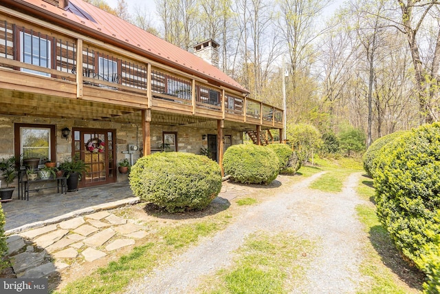 1460 Pitcock Ln, Winchester, VA 22602 - back of house with a wooden deck, stone siding, metal roof, and a chimney