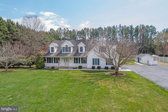 cape cod-style house with driveway, fence, a front lawn, and a porch