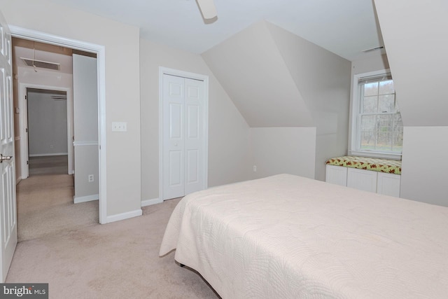 bedroom featuring a closet, visible vents, vaulted ceiling, and light colored carpet