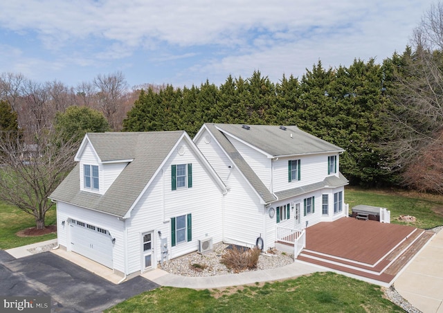 exterior space with a garage, an AC wall unit, aphalt driveway, and roof with shingles