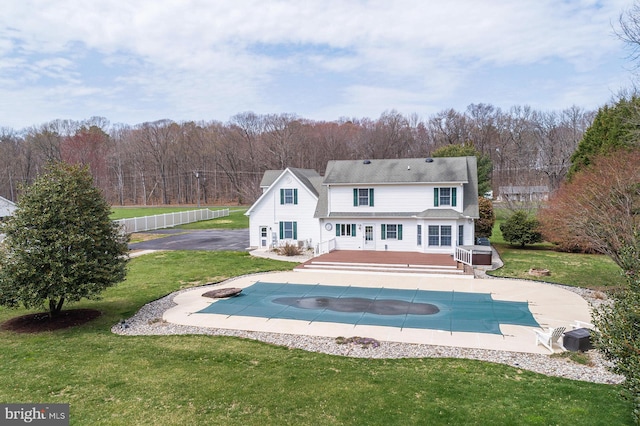 rear view of house with a patio, a lawn, a covered pool, and a wooden deck