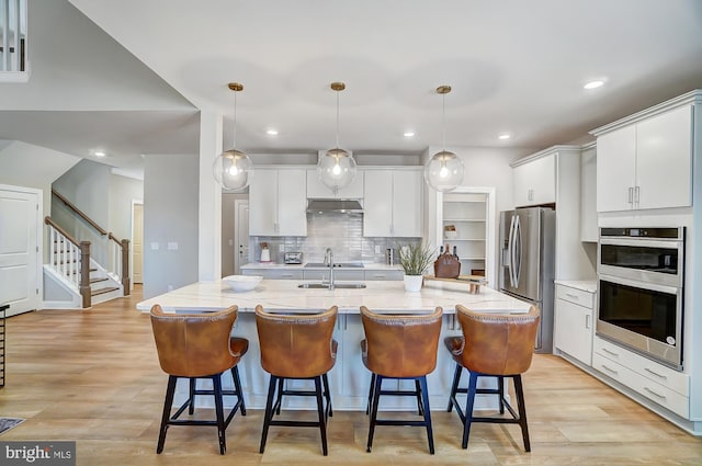 751 Bowie Shop Rd, Huntingtown, MD 20639 - kitchen featuring white cabinets, a breakfast bar area, under cabinet range hood, and stainless steel appliances