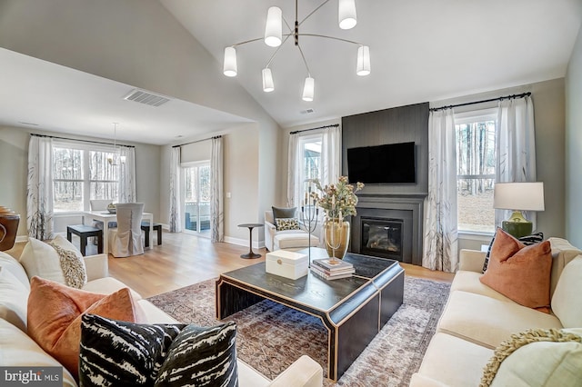 751 Bowie Shop Rd, Huntingtown, MD 20639 - living room featuring visible vents, wood finished floors, a fireplace, a chandelier, and vaulted ceiling