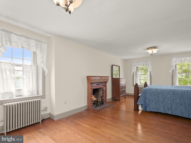 8805 Reichard Rd, Fairplay, MD 21733 - bedroom featuring radiator, light wood-style flooring, a brick fireplace, and a chandelier