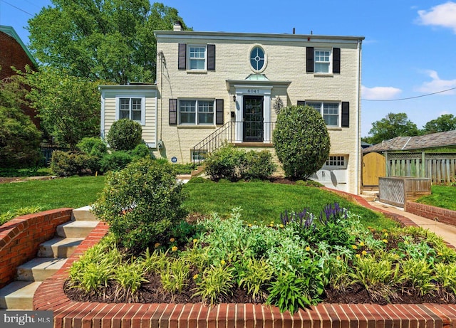 view of front of house featuring fence, a chimney, a front lawn, and brick siding