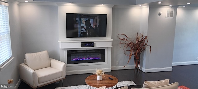 sitting room featuring visible vents, wood finished floors, a glass covered fireplace, and ornamental molding